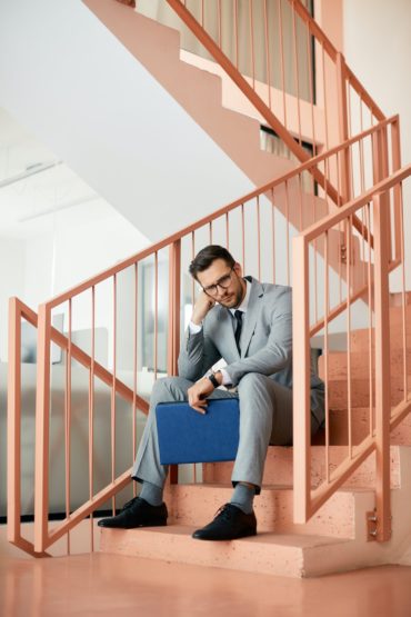 distraught-businessman-sitting-on-staircase-in-a-hallway-.jpg